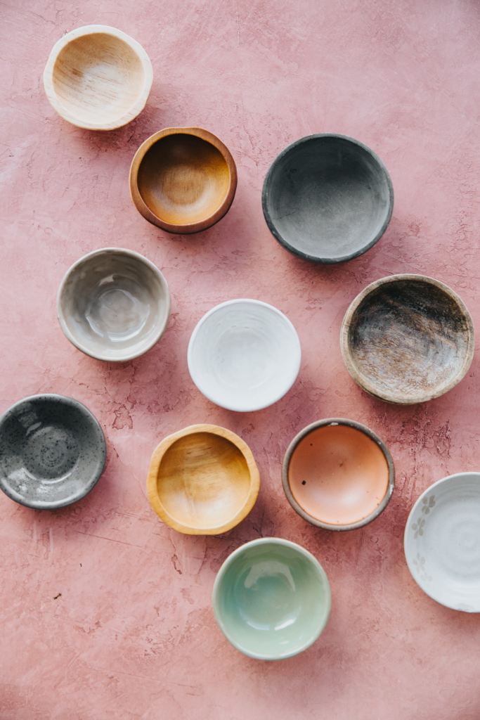 Multicolored ceramic pots on a rose colored backdrop.
