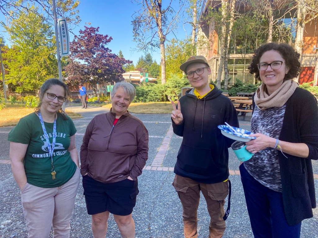 Four staff members smiling in the courtyard.