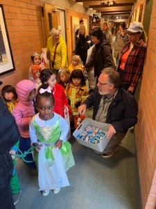 Dr. Kahn handing out candy to cute kids in Halloween costumes from the PCC