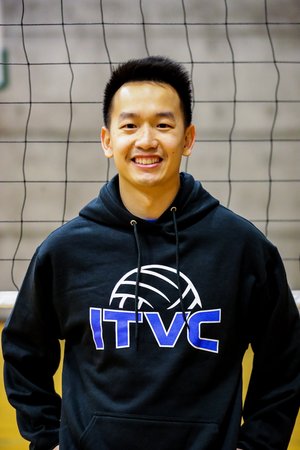 This is an image of Dan wearing a sweatshirt standing in front of a volleyball net.