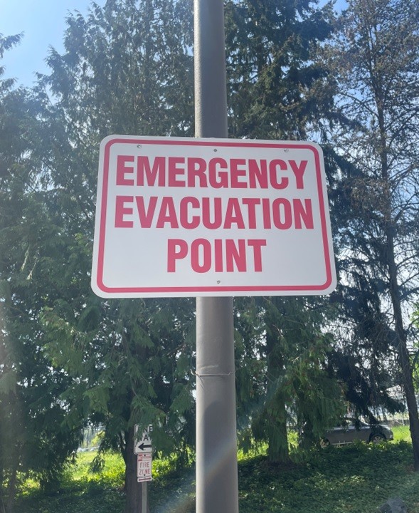 This is a white sign that says "Emergency Evacuation Point" in red