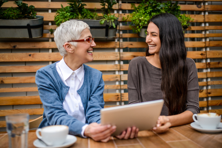 Two women at a table, smiling. 