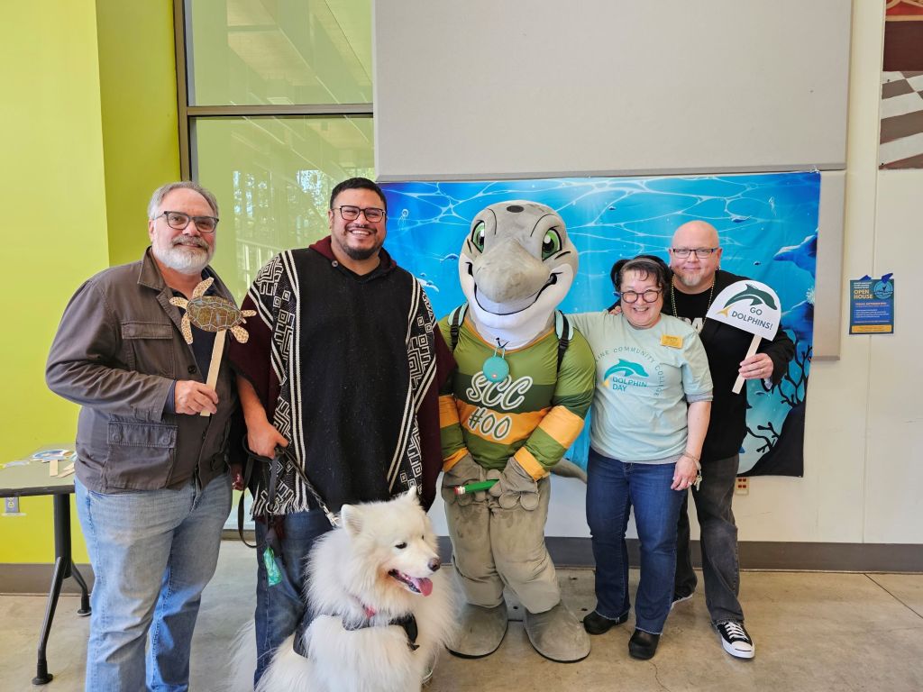 President Kahn, Lori Yonemitsu, VP Ramos, and VP Aiello posing with Dolphie. 