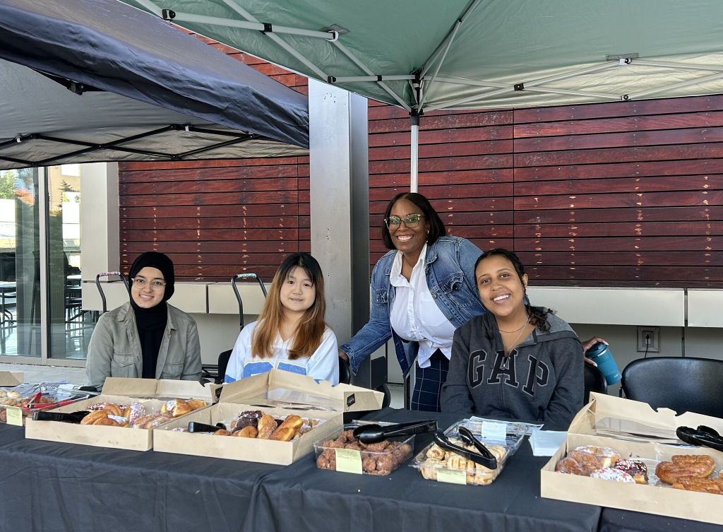 Students and staff at a table giving out pastries.
