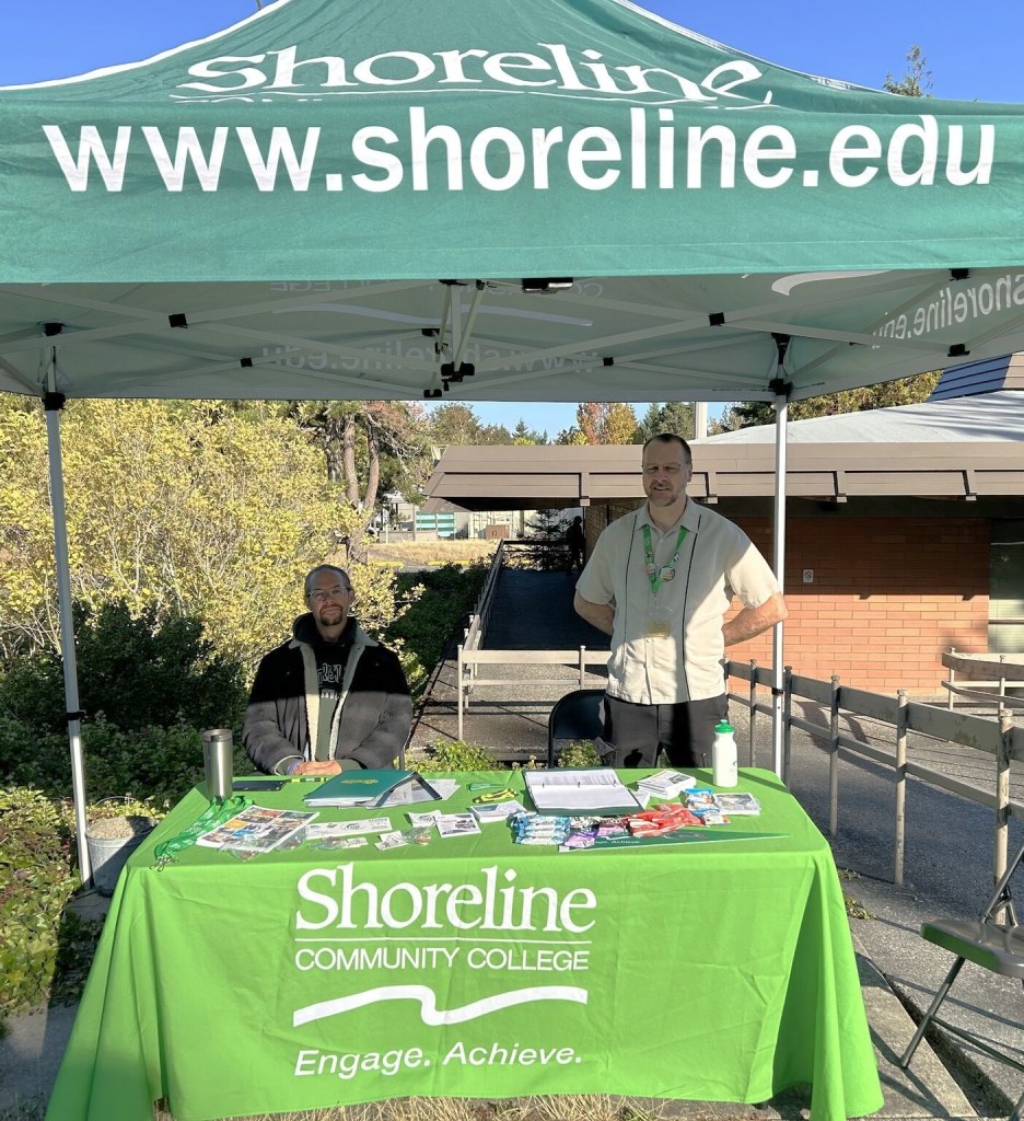 Staff at a welcome table, under a Shoreline tent. 
