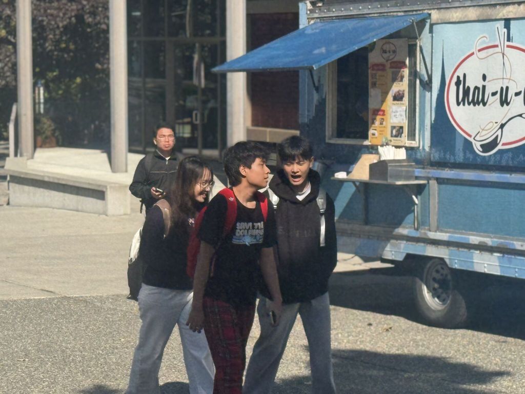 Students walking on campus with a food truck in the background. 