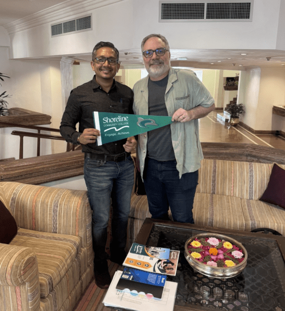 Jack and a colleague in India, holding a Shoreline Community College banner.