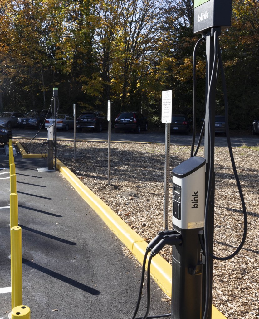 Photo of new charging station with parking lot in the background. 